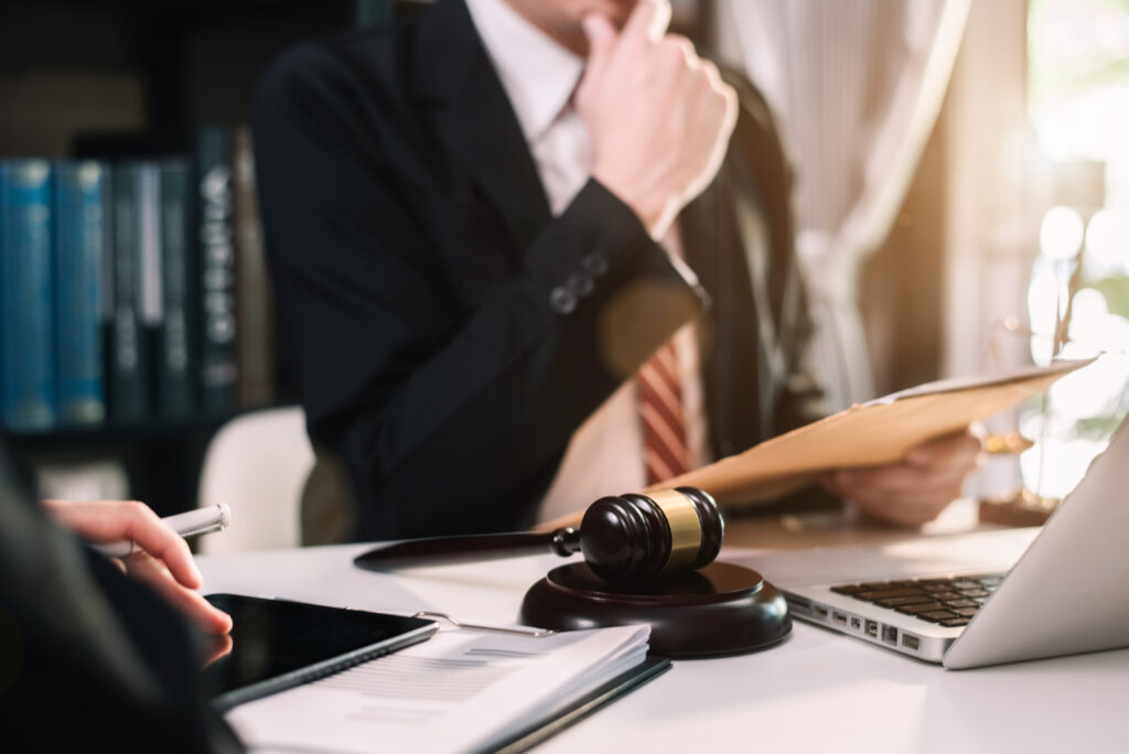 A legal expert consults a client about investor misconduct, with a gavel and legal books in the background.