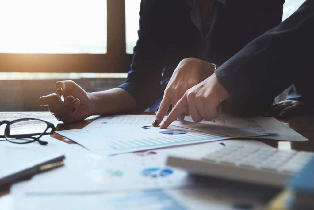 Two professionals point to key data on a financial chart they're discussing.