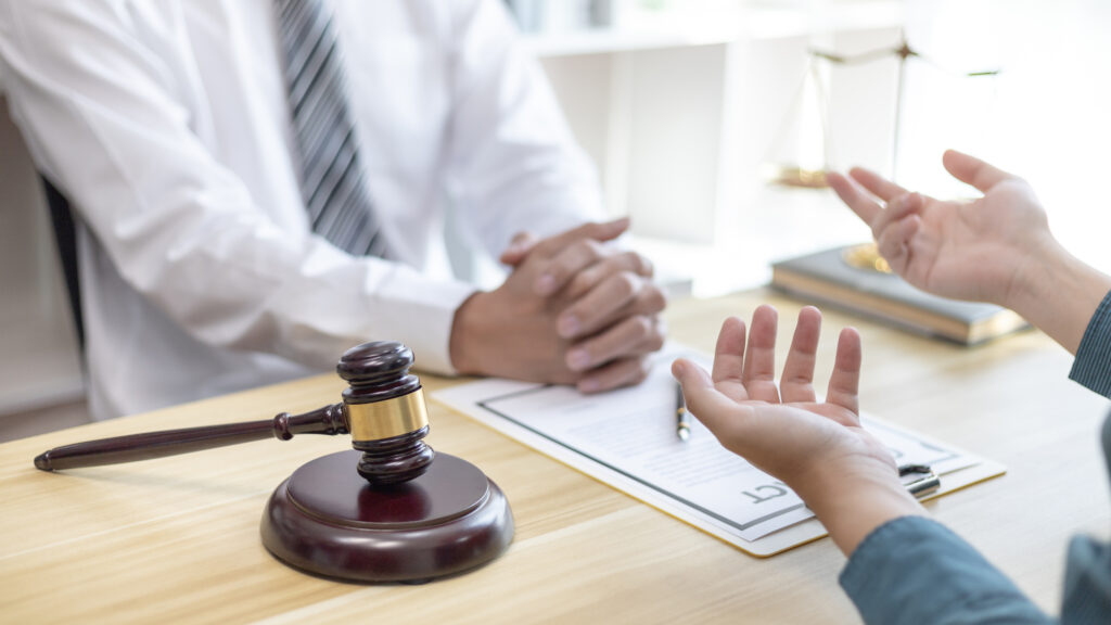 A client explaining their situation to a legal consultant in an office with a gavel on the desk.